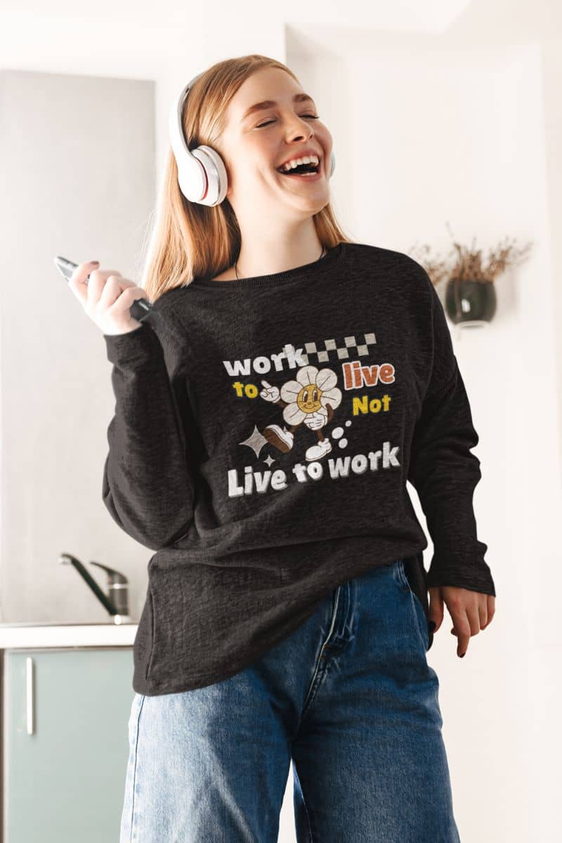self care pullover with a person wearing a black sweatshirt with the quote 'Work to Live, Not Live to Work', laughing indoors.