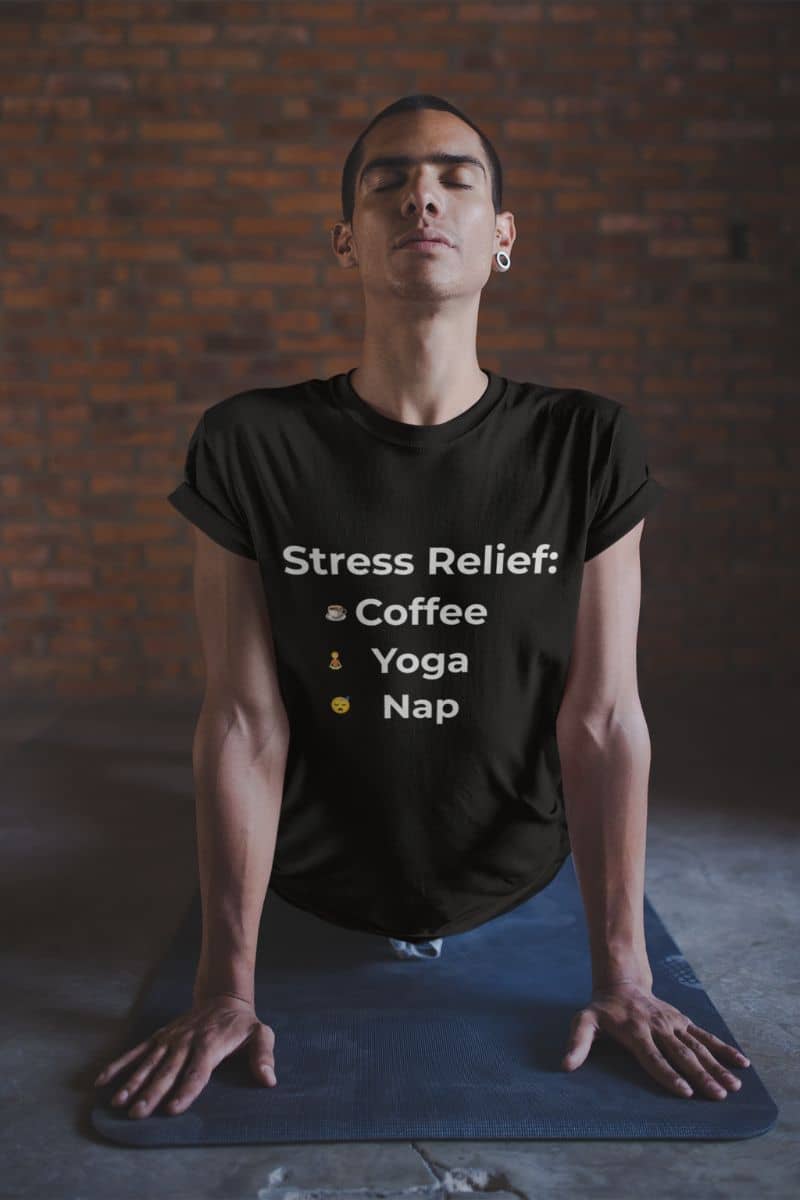 self-care slogan tee with a man in a yoga pose wearing a black t-shirt with 'Stress Relief' text against a brick wall.