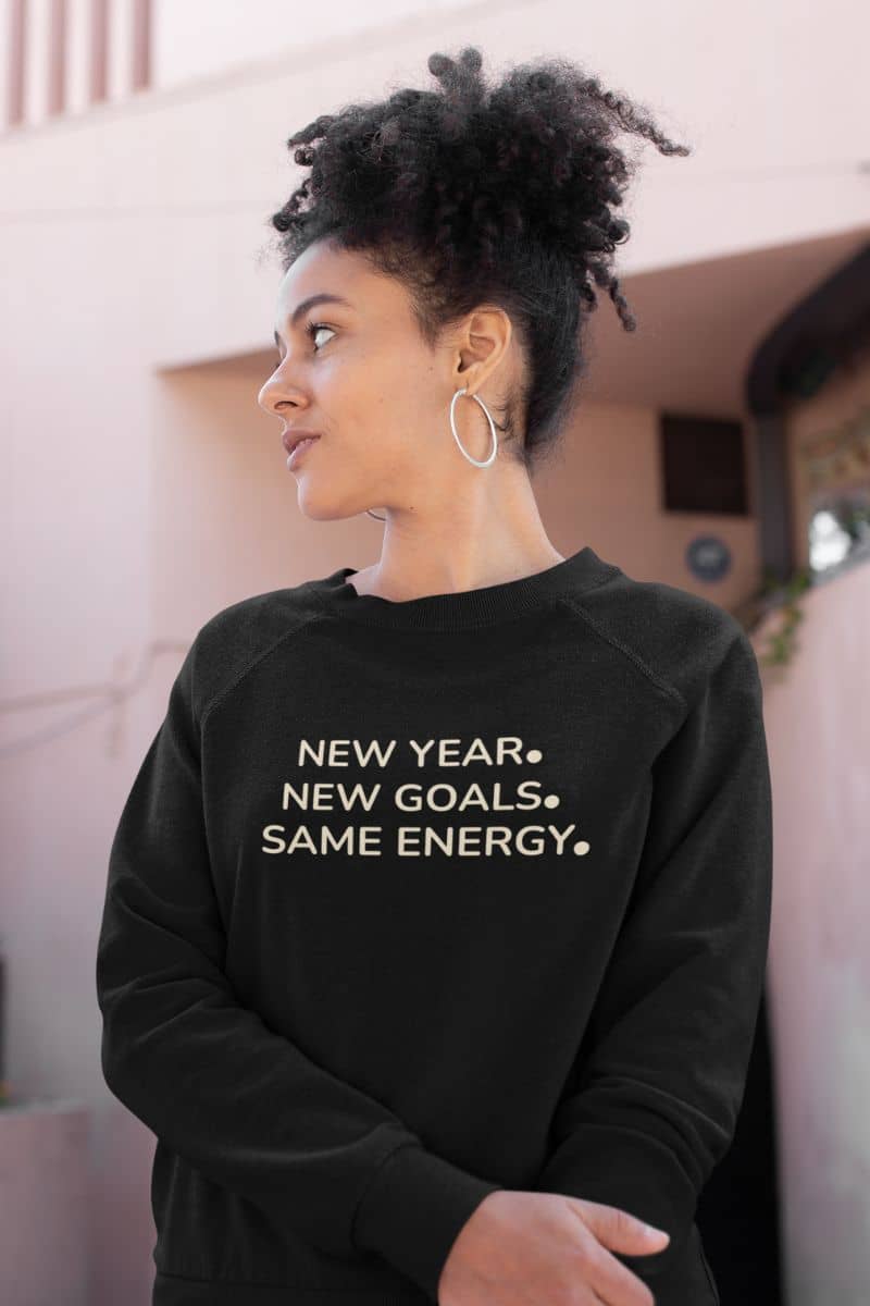 self improvement sweater with a person wearing a black sweatshirt with text 'NEW YEAR. NEW GOALS. SAME ENERGY.'