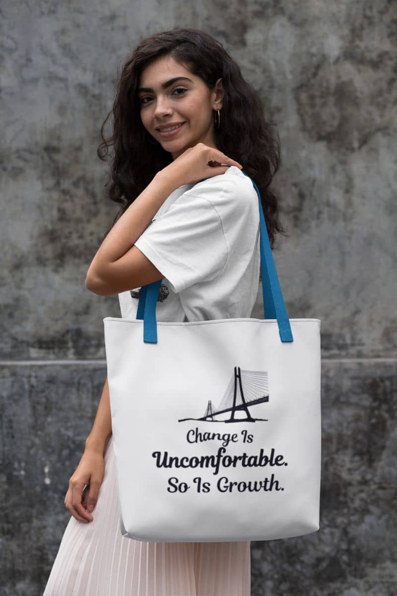 self improvement tote with a woman holding a tote bag with text 'Change Is Uncomfortable. So Is Growth' against a gray wall.