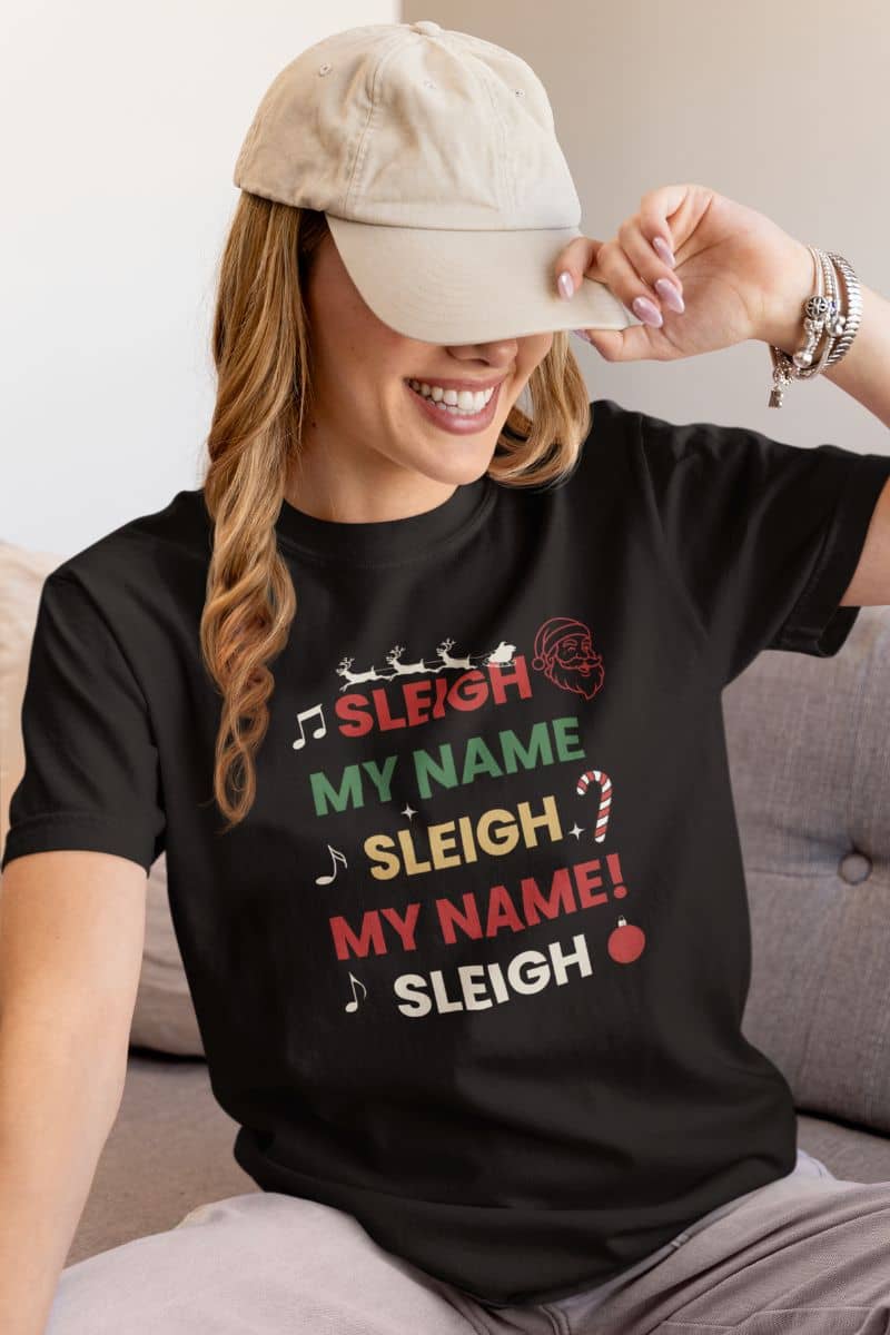 sleigh ride graphic tee with a person wearing a black t-shirt with text 'Sleigh My Name, Sleigh My Name', sitting on a couch.