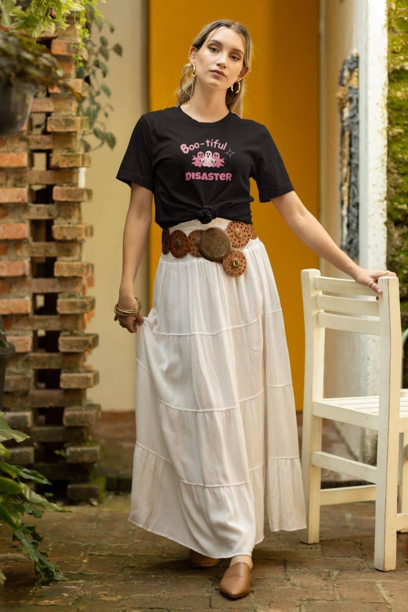 spooky cute tee with a woman in a black t-shirt with text 'Boo-tiful Disaster' and a white skirt standing outdoors.