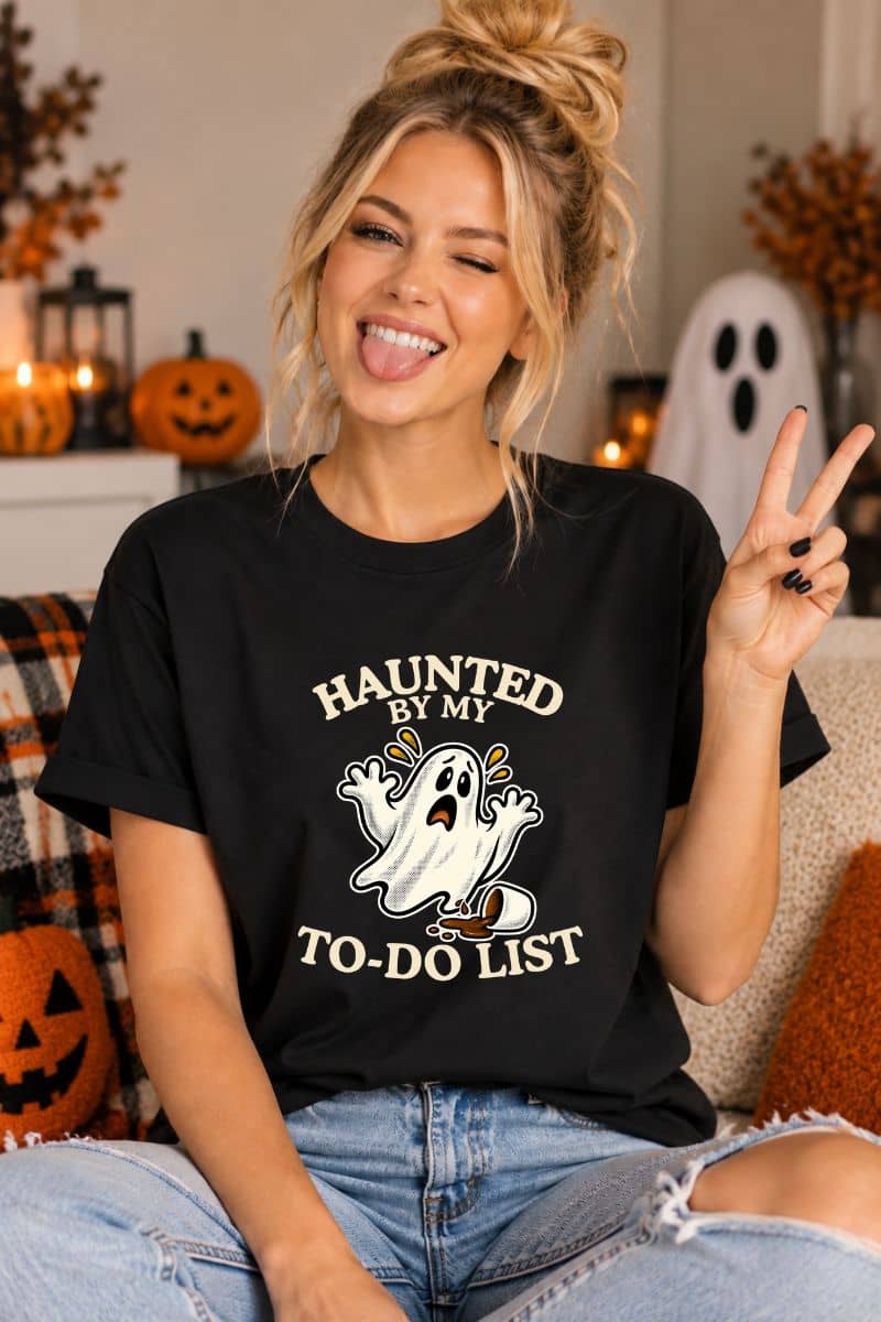 spooky t shirts design featuring a “Haunted by My To-Do List” funny ghost, worn by a woman sitting in a living room