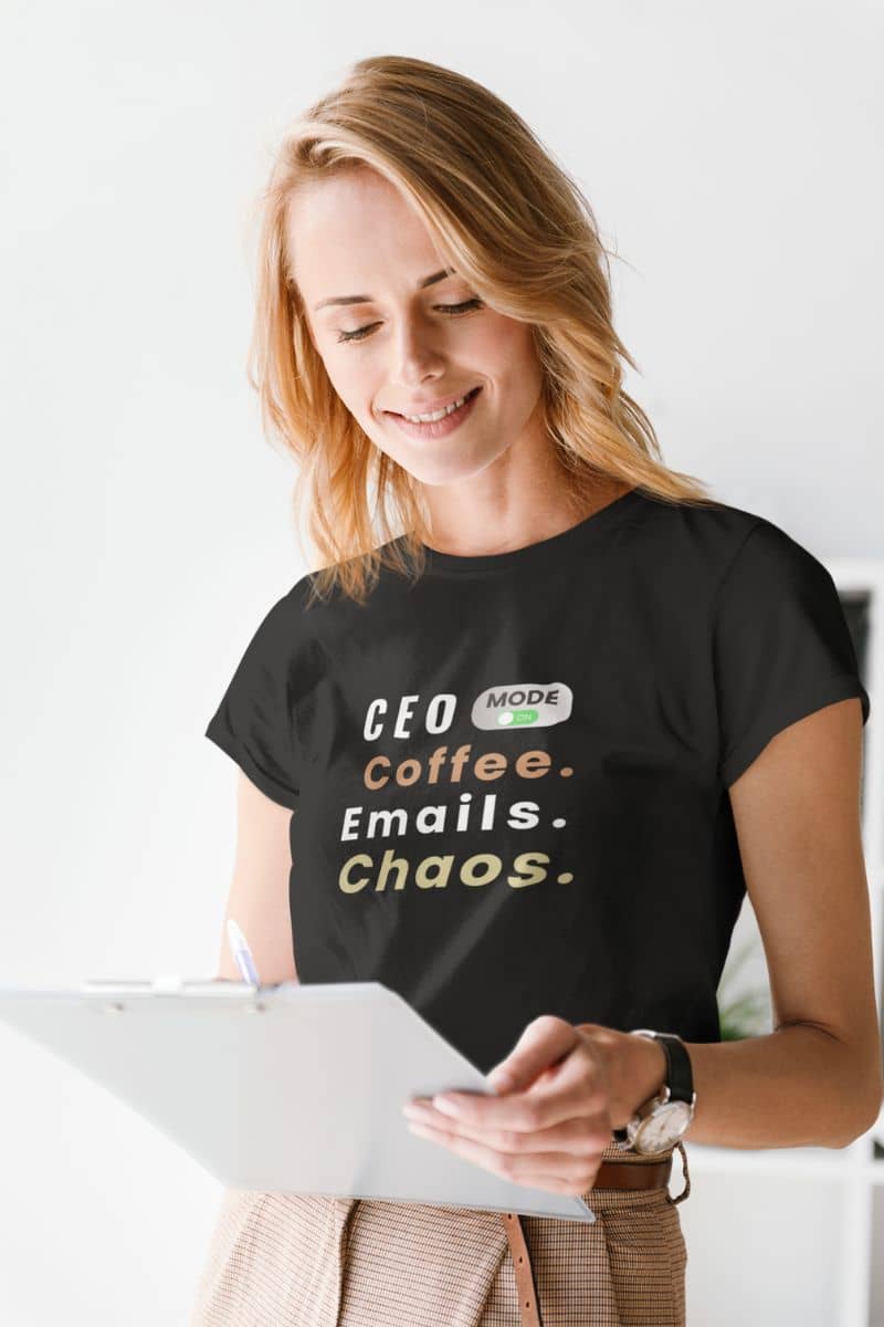 startup humor tee with a woman in a t-shirt with text 'CEO Mode: Coffee. Emails. Chaos.', standing in the meeting room