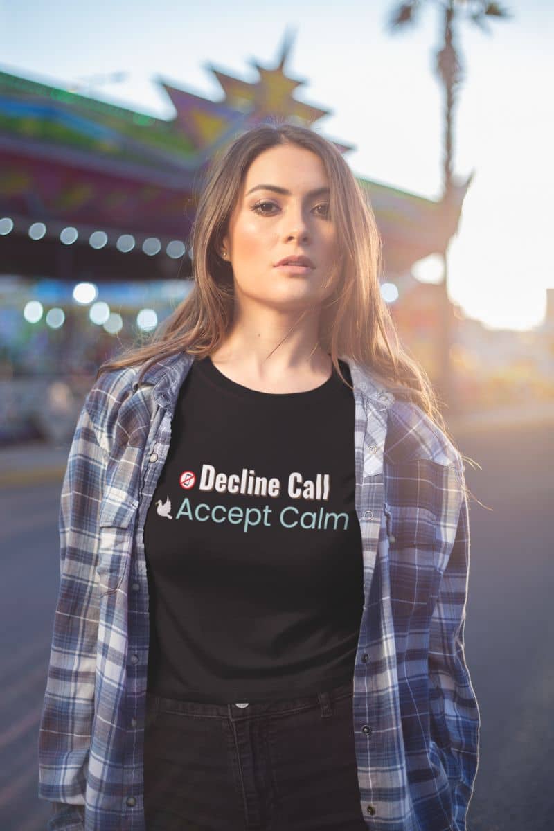 stress relief T-shirt with a woman wearing a black t-shirt with text 'Decline Call, Accept Calm', standing in front of a colorful background.