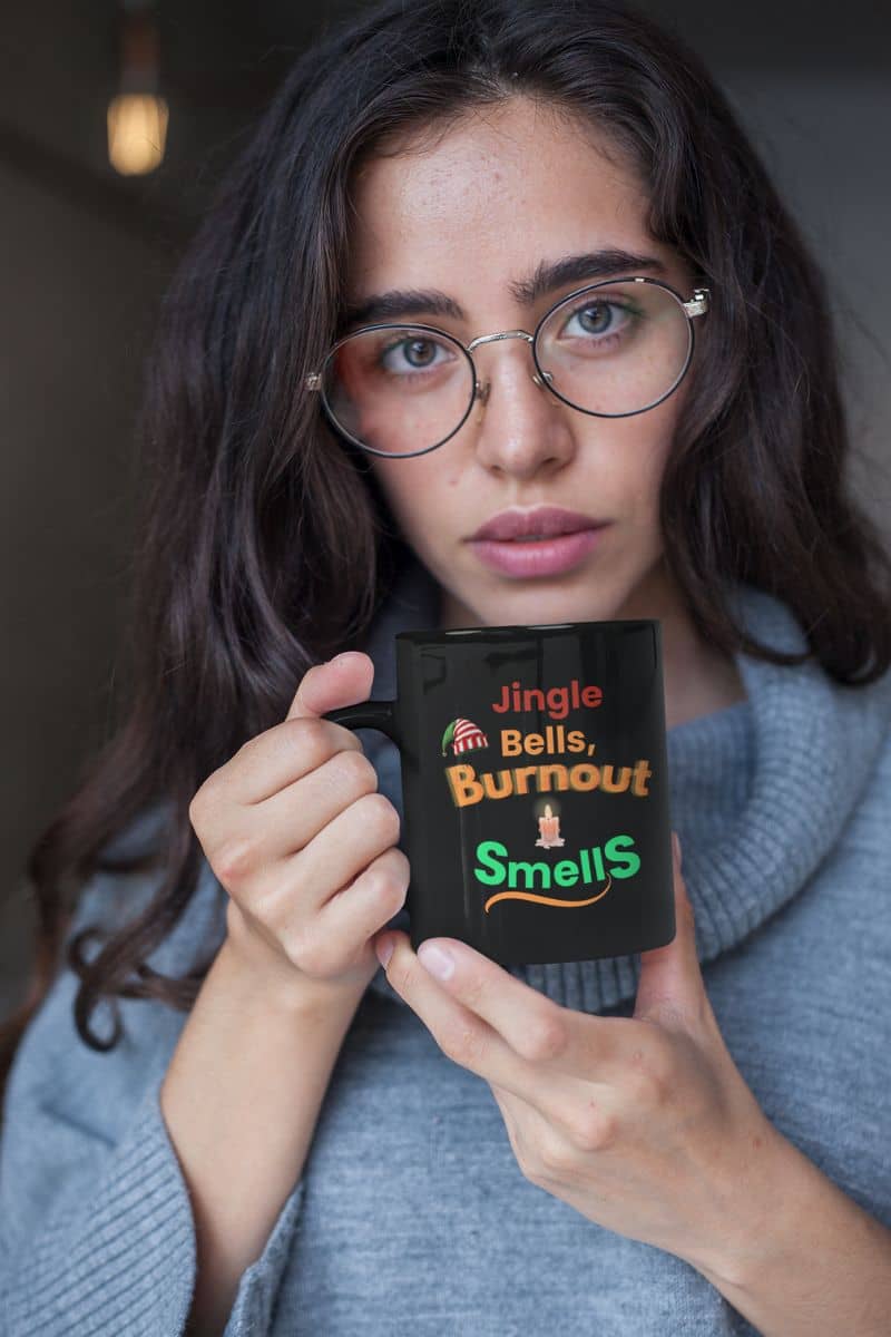stress relief coffee cup with a person holding a mug with humorous text 'Jingle Bells, Burnout Smells'