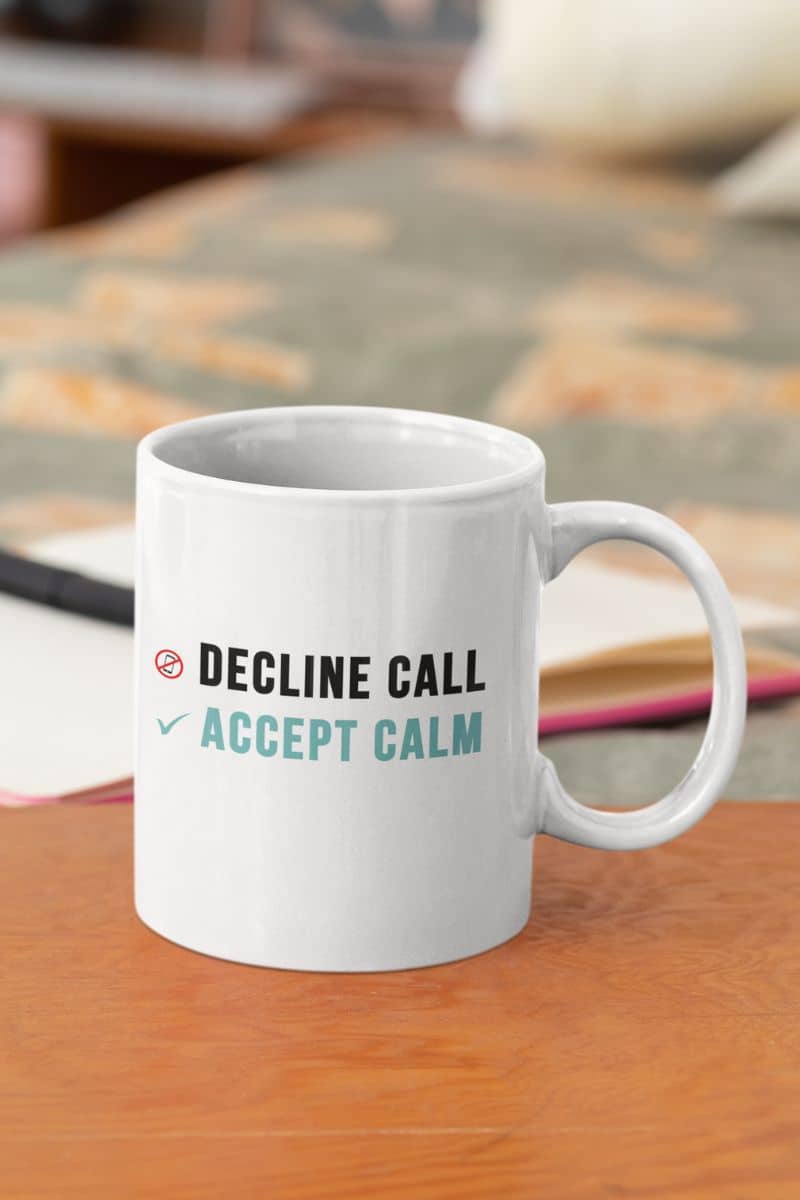 stress relief coffee mug with a white mug with text 'Decline Call Accept Calm' on a wooden surface.