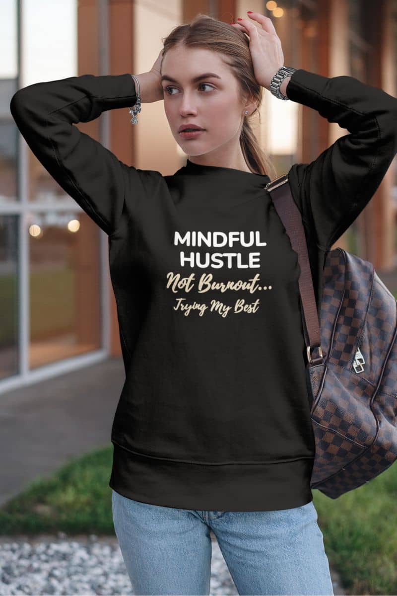 stress relief sweatshirt with a person wearing a black sweatshirt with 'Mindful Hustle Not Burnout... Trying My Best' text, standing outdoors.