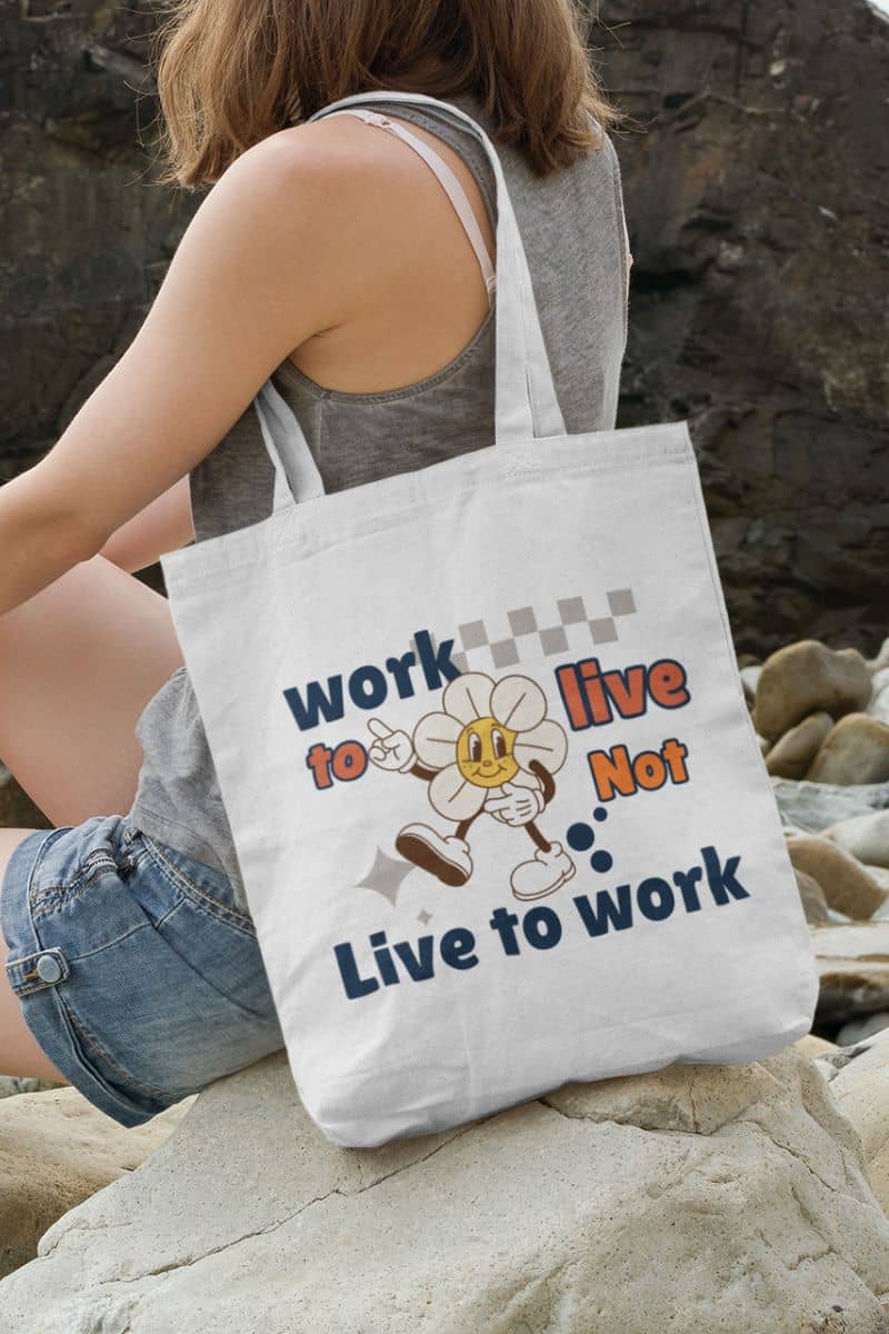 sustainable shopping bag with a person sitting on rocks with a tote bag featuring a motivational quote 'Work to Live, Not Live to Work' and cartoon character.