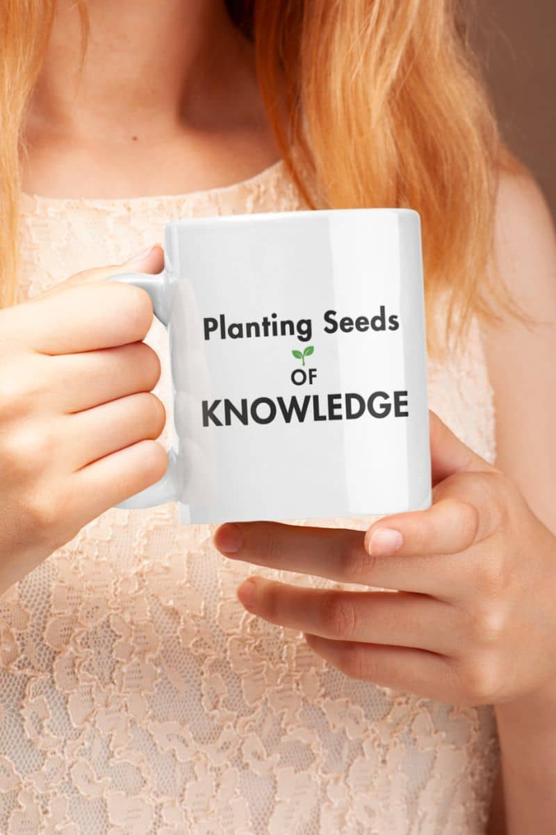 teacher appreciation mug with a person holding a white mug with the printed phrase 'Planting Seeds OF KNOWLEDGE' 