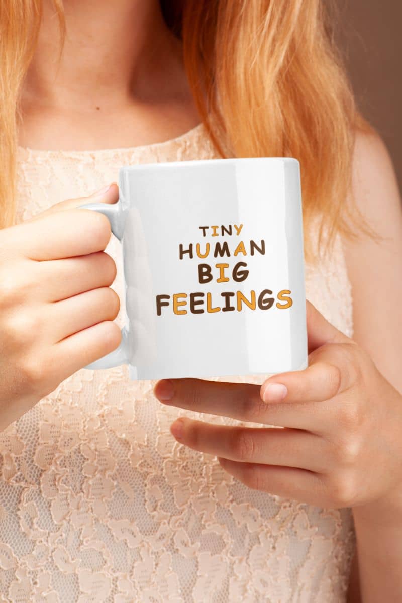 teacher coffee mug with a person holding a white ceramic mug with the text 'TINY HUMAN BIG FEELINGS' 