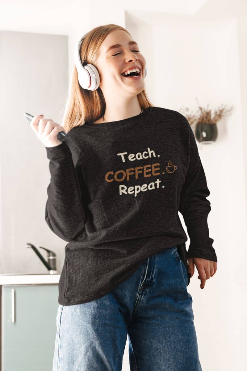 teacher sweatshirt with a woman wearing a black sweatshirt featuring the text 'Teach. Coffee. Repeat.'
