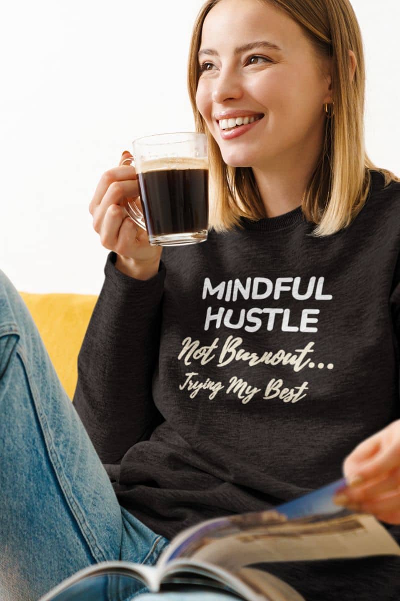 tired but trying sweatshirt with a woman wearing a black sweatshirt with 'Mindful Hustle – Not Burnout… Trying My Best'.