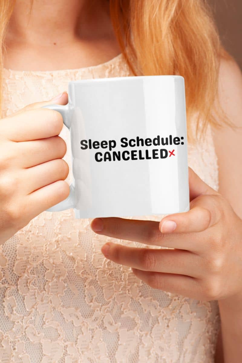 tired coffee mug with a person holding a white mug with 'Sleep Schedule: CANCELLED' text