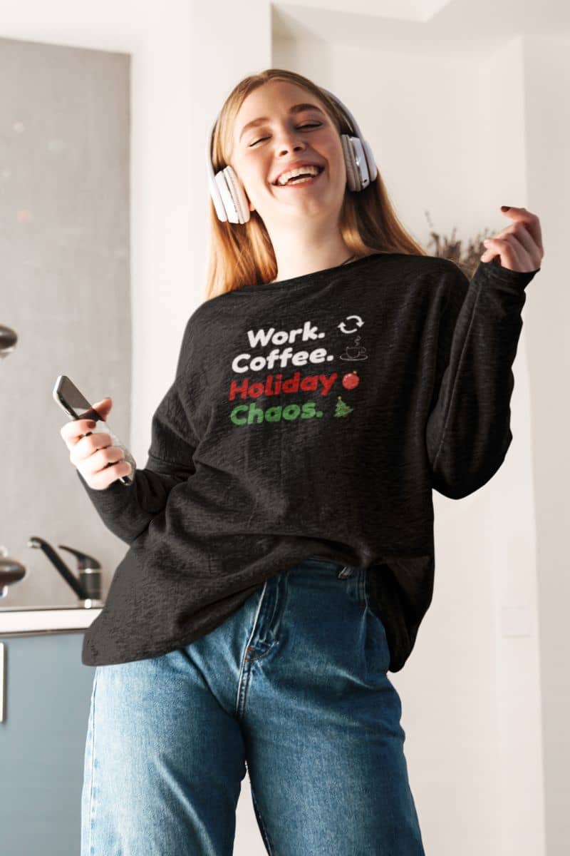 tired holiday sweatshirt with a person wearing a black sweatshirt with text 'Work. Coffee. Holiday Chaos.', standing in a kitchen.