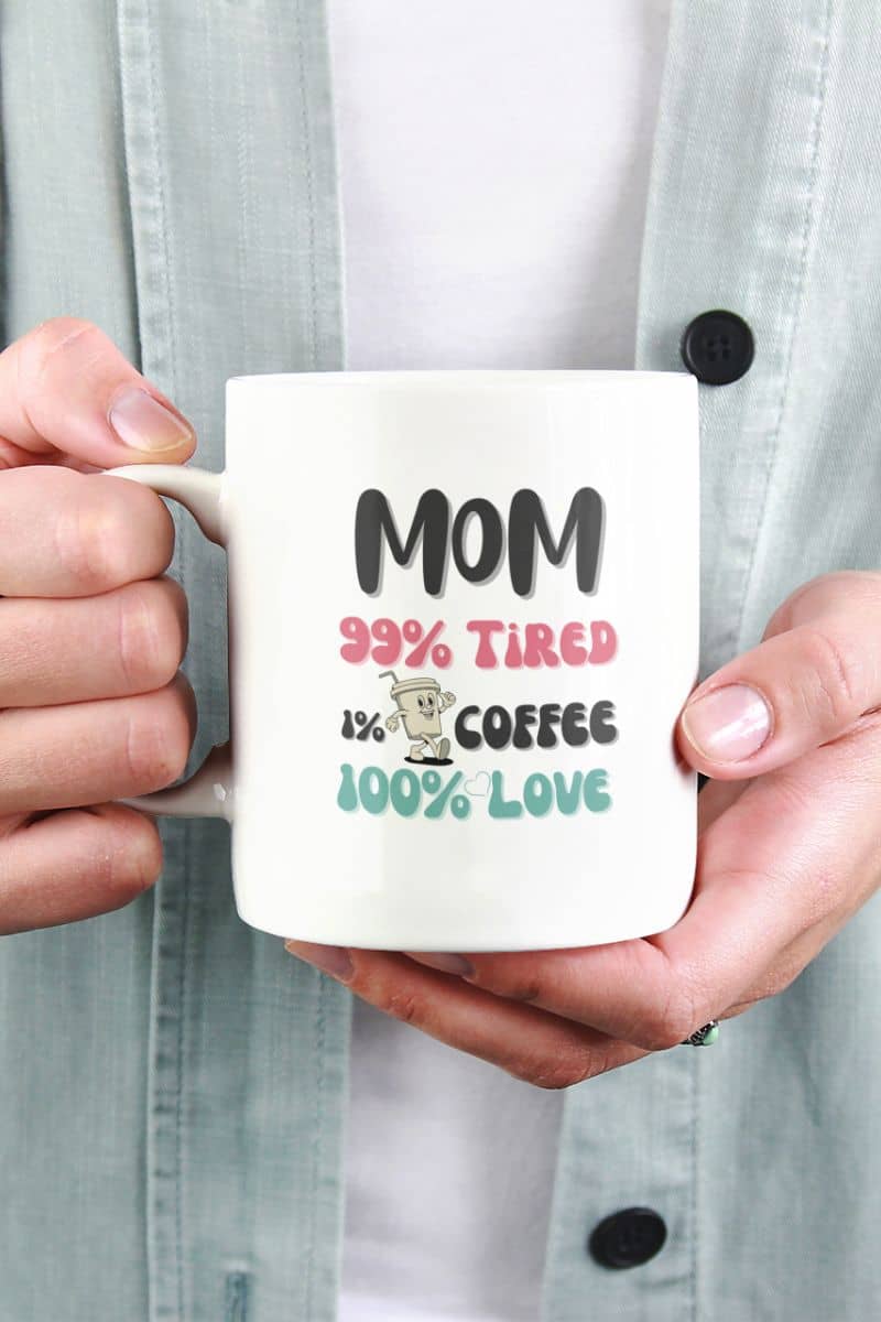tired mom coffee cup with a person holding a mug with a humorous text 'Mom 99% Tired, 1% Coffee, 100% Love'