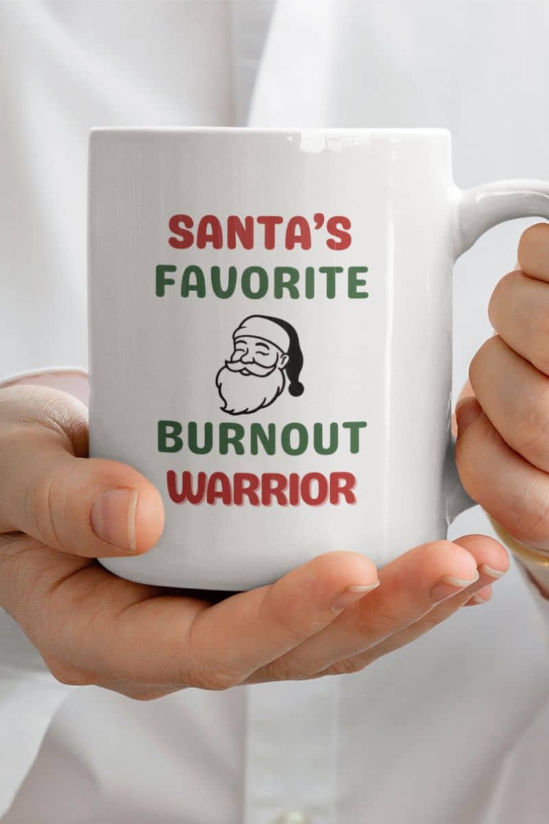 tired santa coffee mug with a white mug featuring the text 'Santa's Favorite Burnout Warrior' held by hands against a white background