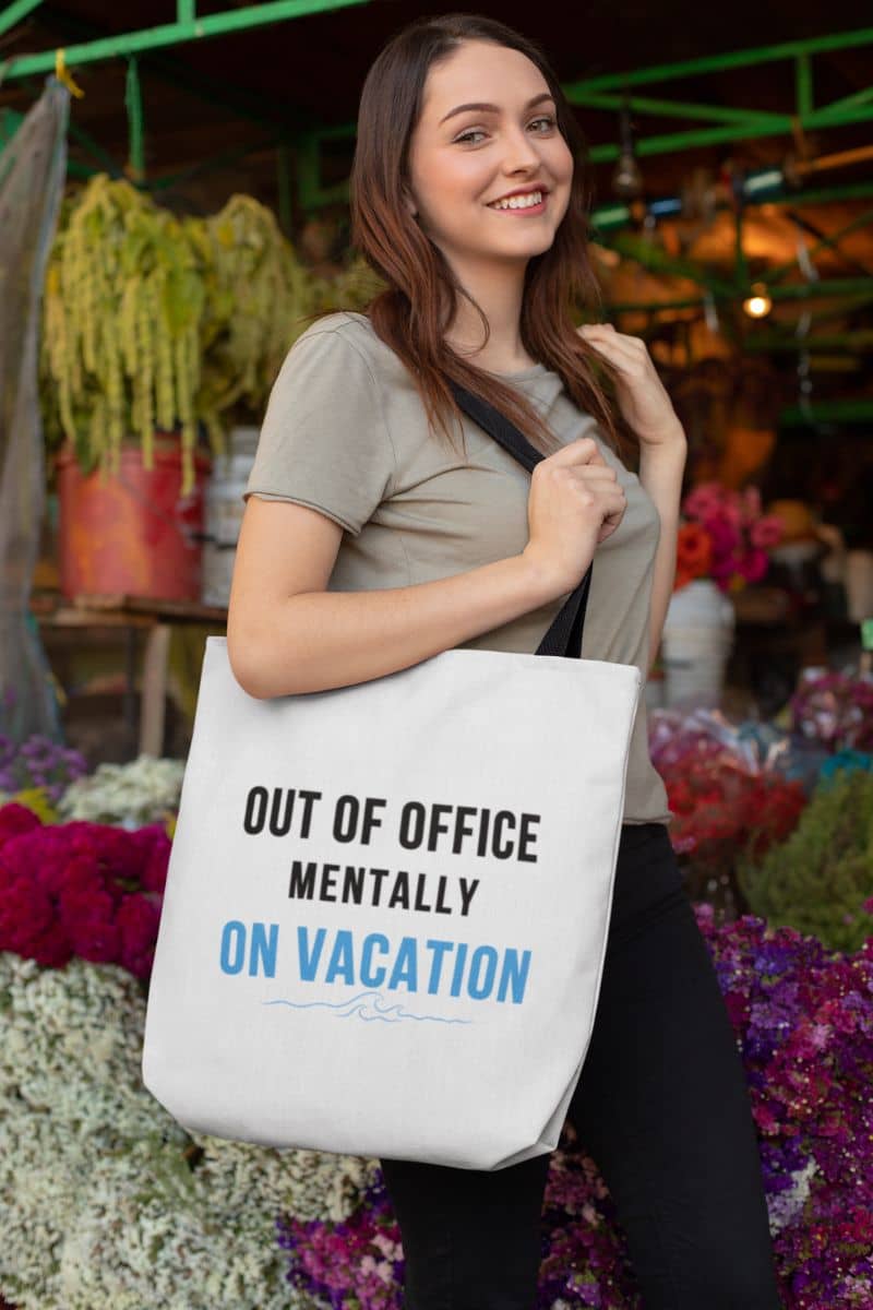travel tote bag with a woman holding a tote bag with text 'Out of Office: Mentally on Vacation' in a market setting