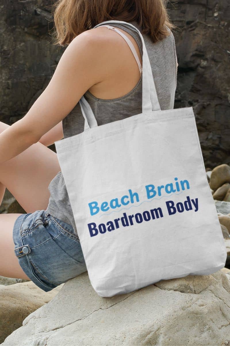 vacation shopper bag with a person sitting on rocks with a tote bag labeled 'Beach Brain Boardroom Body' on a rocky background