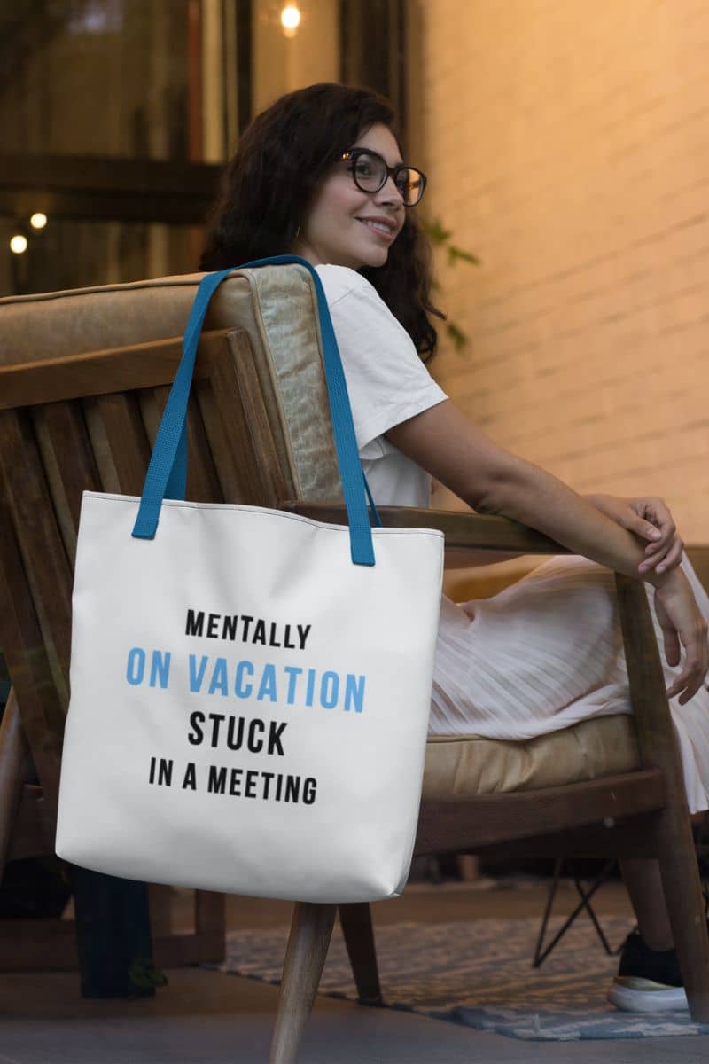 vacation tote bag with a person sitting on a chair with a tote bag that says 'Mentally on vacation stuck in a meeting'.