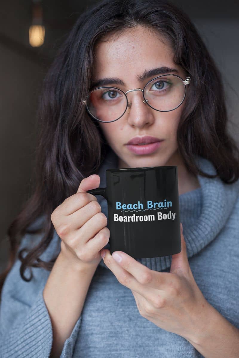 wanderlust ceramic mug with a person holding a mug with text 'Beach Brain Boardroom Body' while wearing glasses.