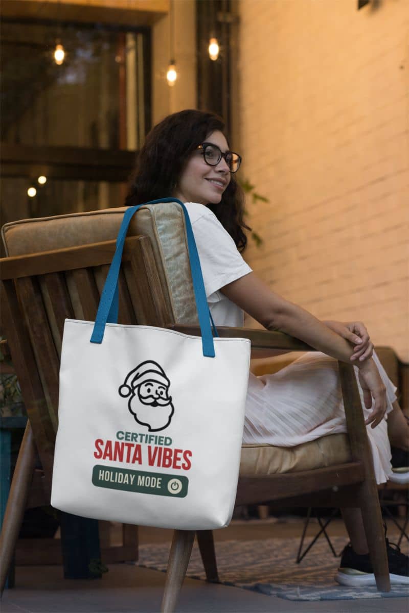 winter vibes tote bag with a woman sitting on a chair holding a tote bag with 'Certified Santa Vibes – Holiday Mode On' text.