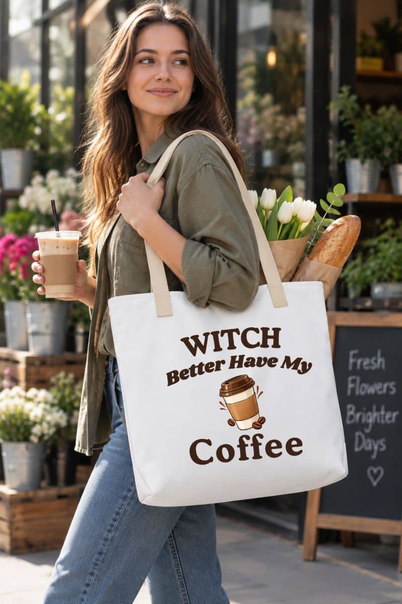 witch coffee tote bag with a woman carrying a white canvas tote bag featuring the text 'Witch Better Have My Coffee' and a coffee cup graphic, standing in front of a flower shop.