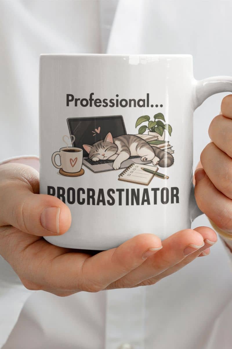 work from home coffee mug with a white ceramic mug with a 'Professional Procrastinator' design, held by two hands against a white shirt background. 