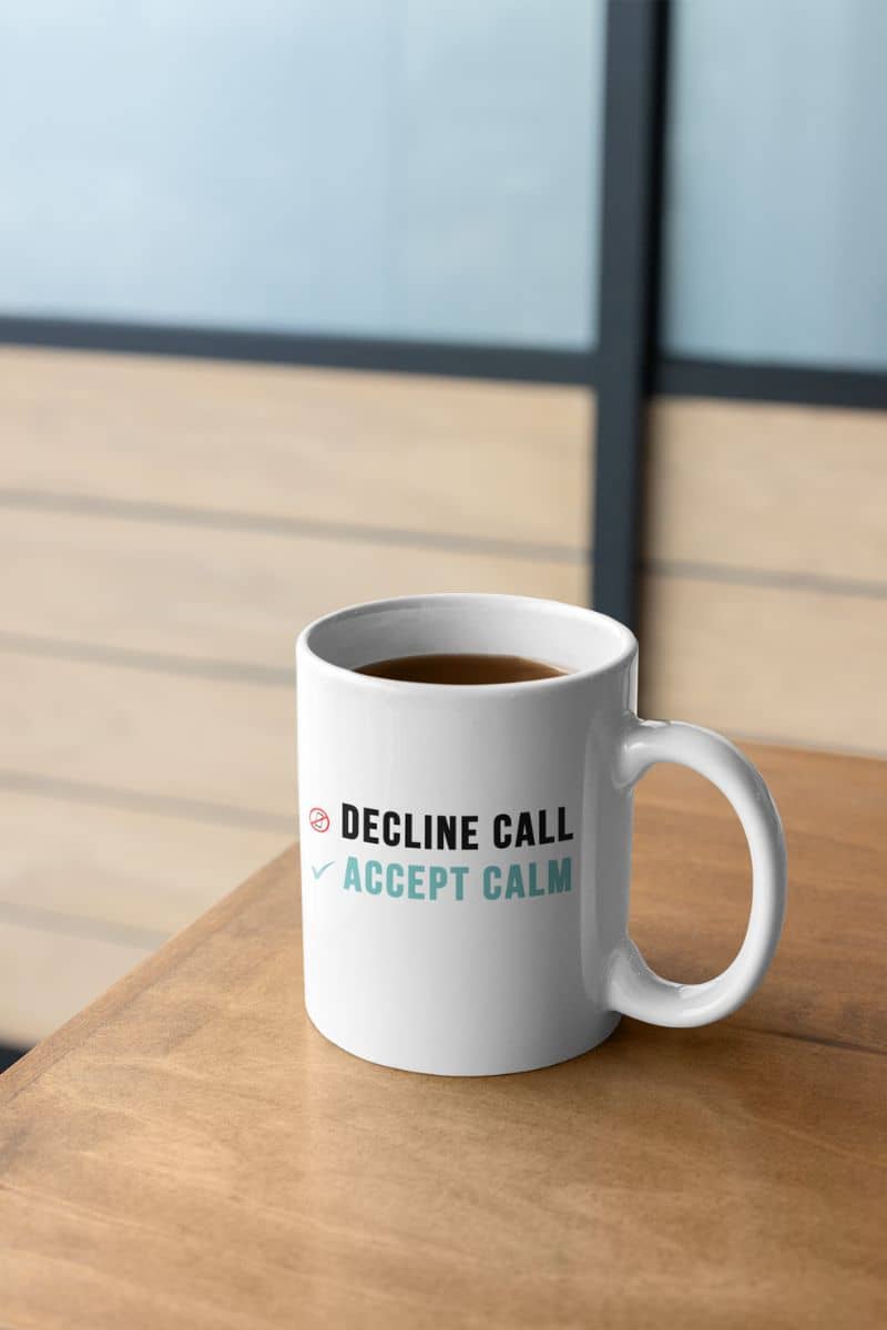 work from home mug with a white mug with text 'Decline call, accept calm' on a wooden surface.