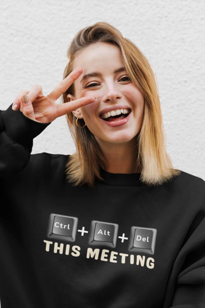 work humor sweatshirt with a person wearing a black sweatshirt with text 'Ctrl + Alt + Del This Meeting', making a peace sign.