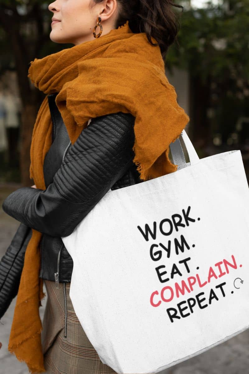 work life humor tote with a person wearing a mustard yellow scarf and holding a tote bag with text.