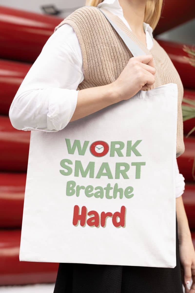 Work quote tote bag for office staff with a person holding a tote bag with 'Work Smart Breathe Hard' text against a red background