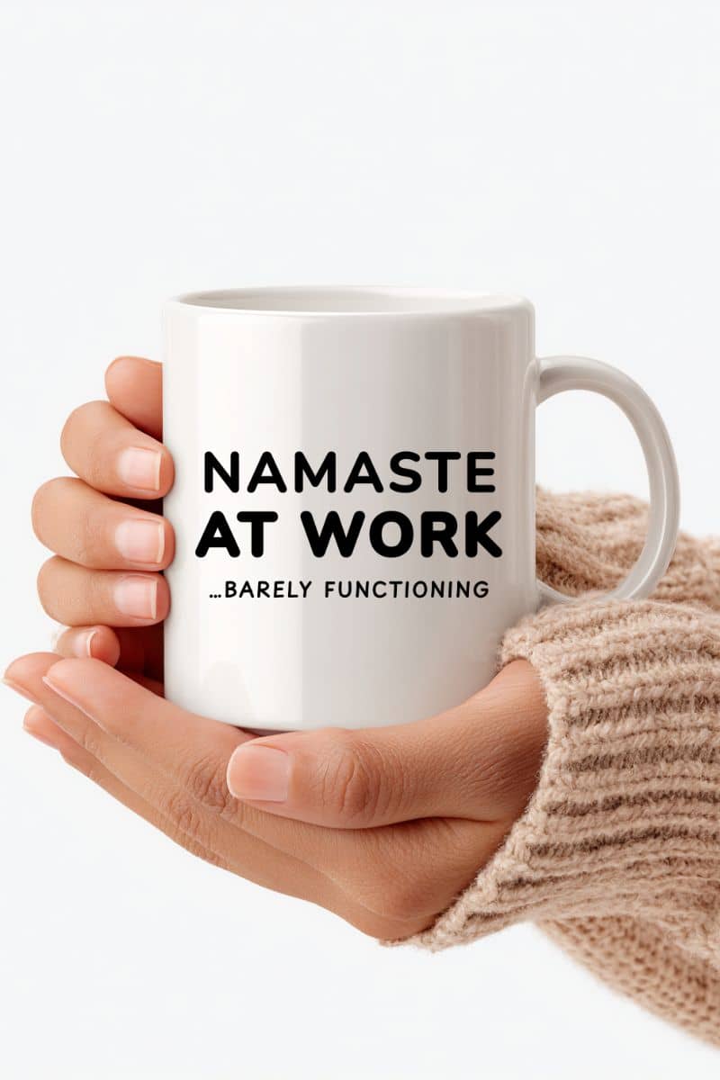 work stress mug with a white mug with 'Namaste at Work... Barely Functioning' text held by a person.