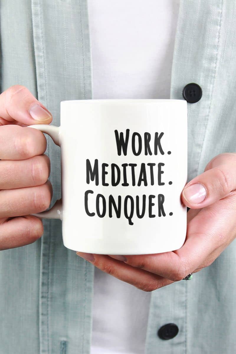 work stress relief mug with a person holding a mug with 'Work. Meditate. Conquer.' text