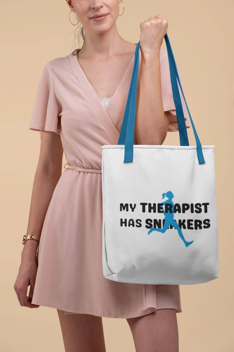 workout lifestyle tote with a woman holding a tote bag with text 'My Therapist Has Sneakers' and a graphic on a beige background