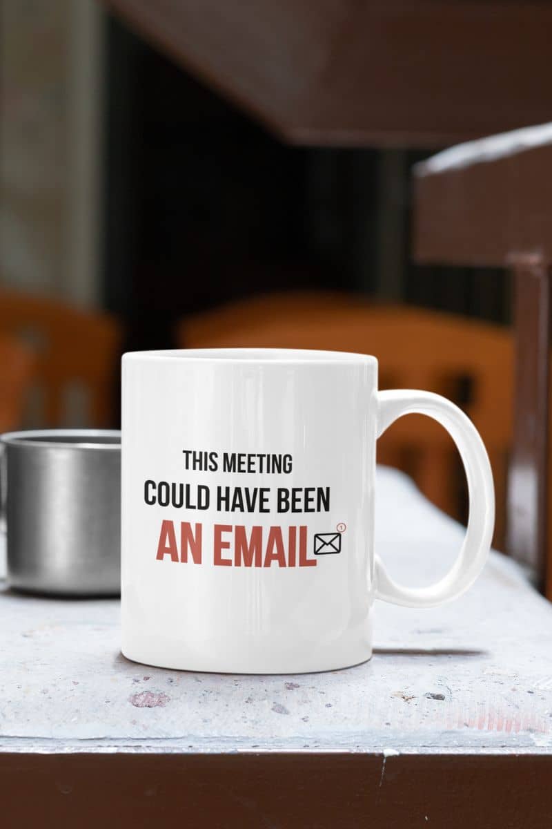 workplace humor mug with a white mug with text 'This meeting could have been an email' on a table.
