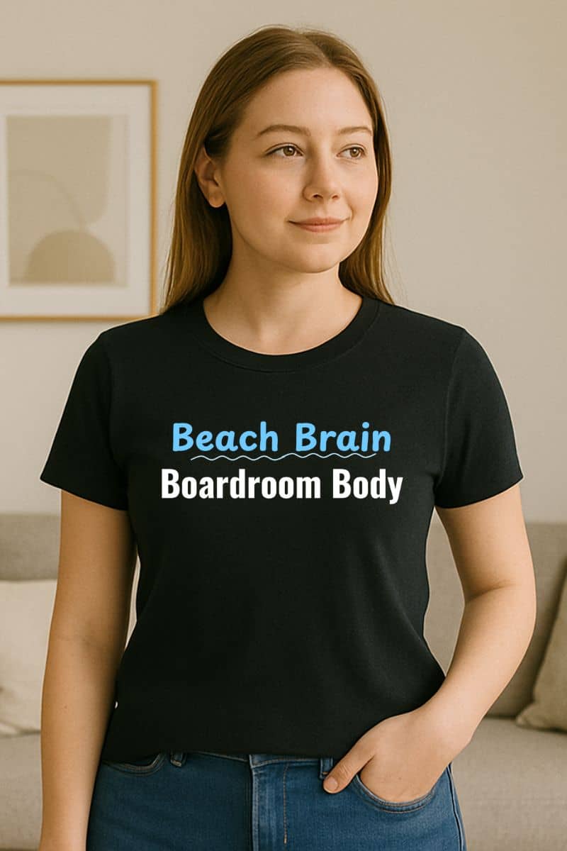 workplace humor shirt with a person wearing a black t-shirt with 'Beach Brain Boardroom Body' text in a living room.