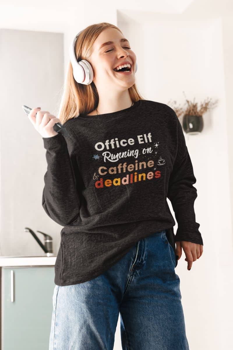 workplace humor sweatshirt with a person in a black sweatshirt featuring text 'Office Elf, Running on Caffeine & Deadlines' in a kitchen