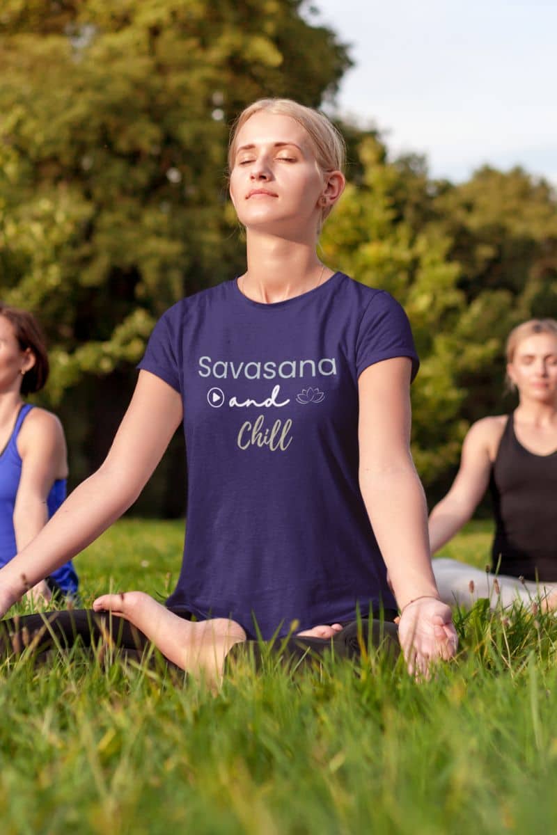 zen lifestyle shirt with a person meditating outdoors wearing a purple t-shirt with 'Savasana and Chill' text.
